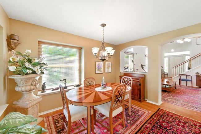 Dining room featuring a chandelier, light wood-style flooring, arched walkways, and stairway | Image 10