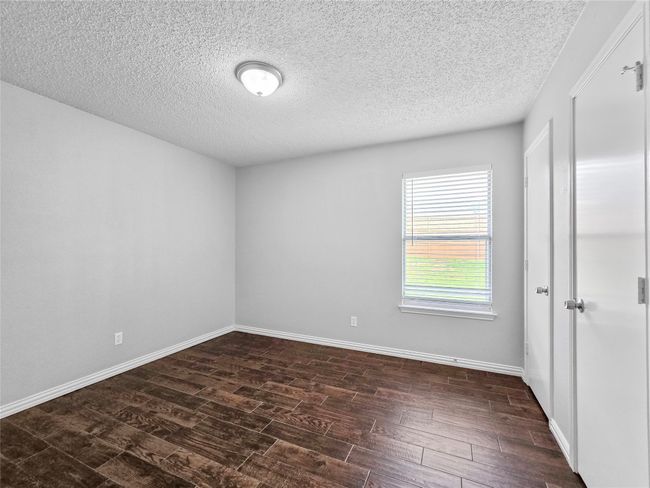 Empty room featuring dark wood finished floors, a textured ceiling, and baseboards | Image 9