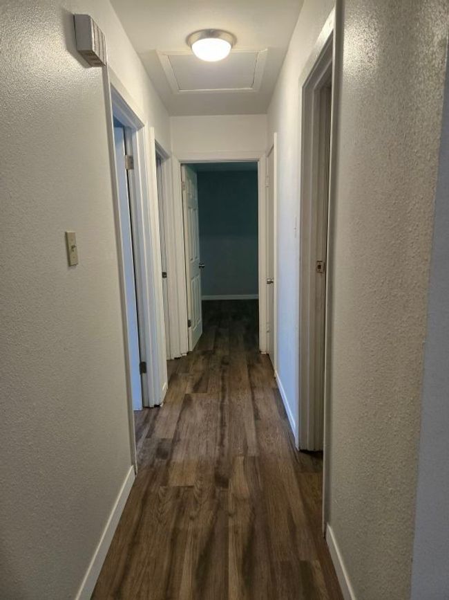 Hallway featuring dark wood-style flooring, attic access, and a textured wall | Image 11
