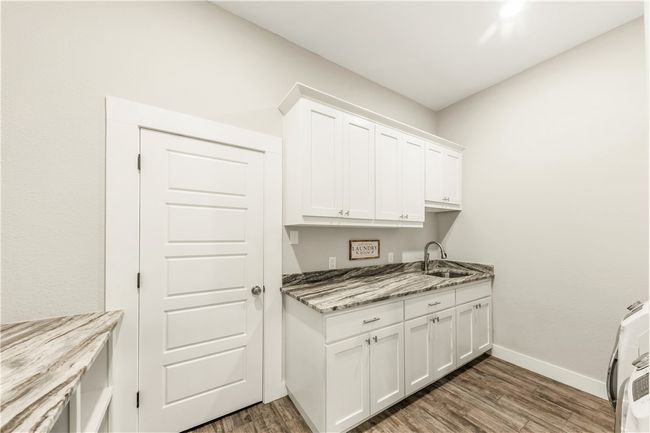 Laundry area with light wood-style floors, cabinet space, and baseboards | Image 14