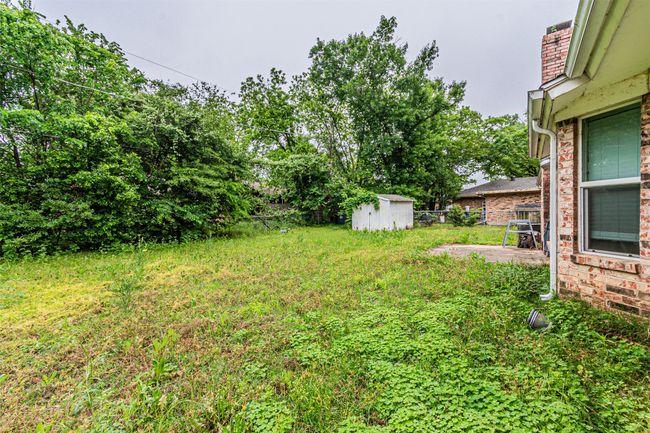 View of yard featuring a patio, fence, an outdoor structure, and a storage shed | Image 29