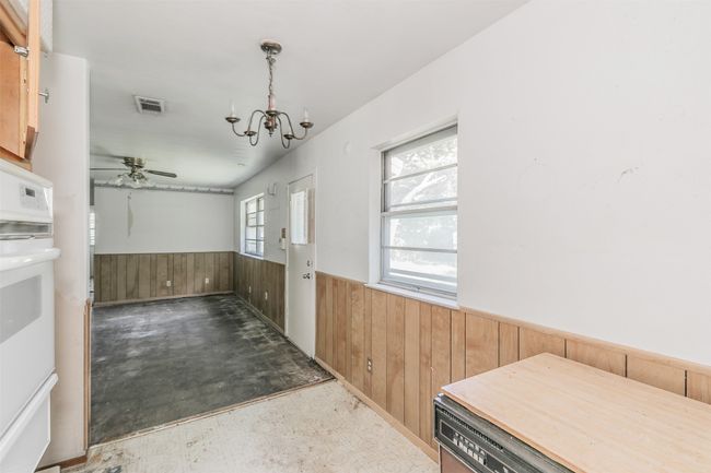 Unfurnished dining area with wainscoting, wood walls, a chandelier, ceiling fan, and tile patterned floors | Image 20