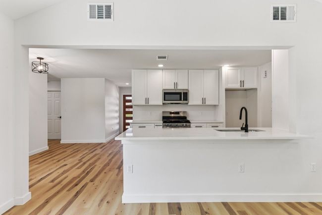 Kitchen featuring white cabinets, stainless steel appliances, light wood-type flooring, light stone counters, and a​​‌​​​​‌​​‌‌​‌‌​​​‌‌​​‌‌​‌​​​​​‌ peninsula | Image 19