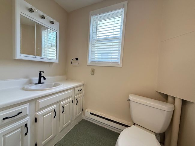 Half bath with baseboard heating, a healthy amount of sunlight, vanity, and toilet | Image 4