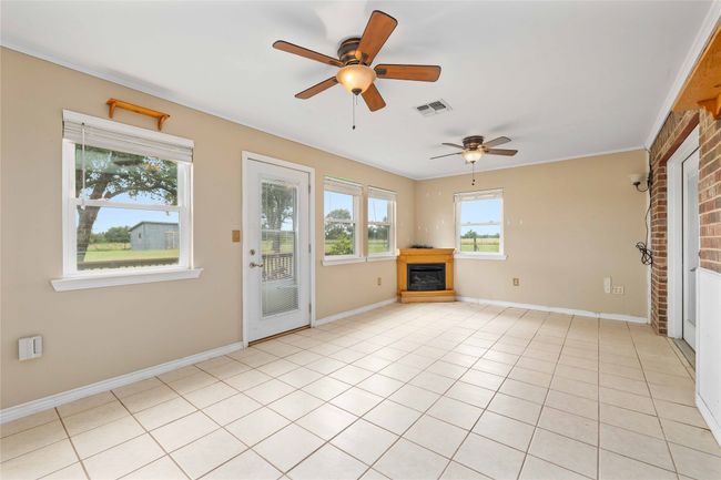 Unfurnished living room with a glass covered fireplace, ceiling fan, and light tile patterned floors | Image 19