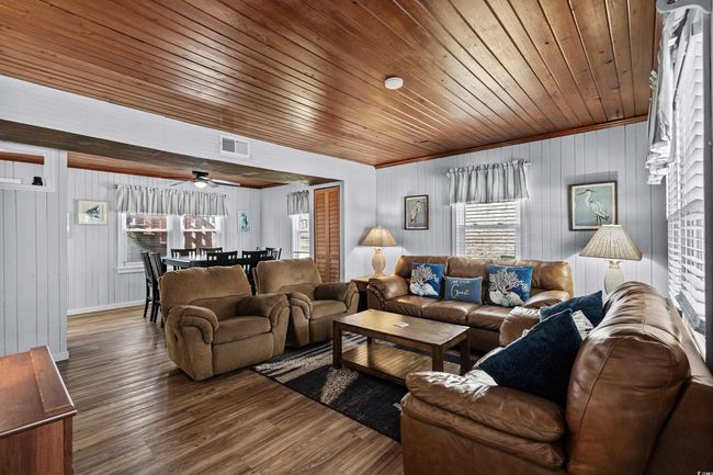 Living area featuring wood finished floors, wooden ceiling, wood walls, ceiling fan, and baseboards | Image 4