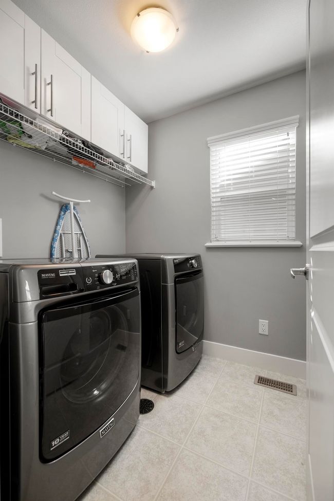 Clothes washing area featuring light tile patterned floors, visible vents, cabinet space, and separate washer and dryer | Image 29
