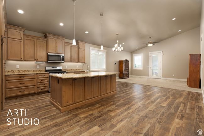 Kitchen with stainless steel appliances, dark wood-style flooring, ceiling fan, a kitchen island with sink, and vaulted ceiling | Image 13
