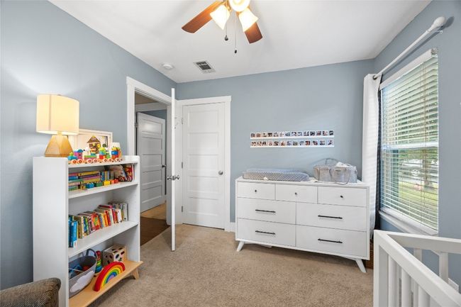 Bedroom featuring light carpet, a ceiling fan, and a nursery area | Image 13