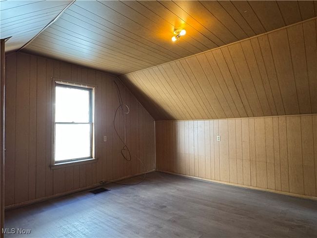 Bonus room featuring lofted ceiling, wooden walls, visible vents, and wood finished floors | Image 28