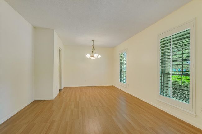Empty room with light wood finished floors, a chandelier, and baseboards | Image 7