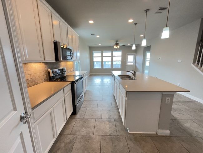 Kitchen with appliances with stainless steel finishes, recessed lighting, a ceiling fan, backsplash, and white cabinetry | Image 7