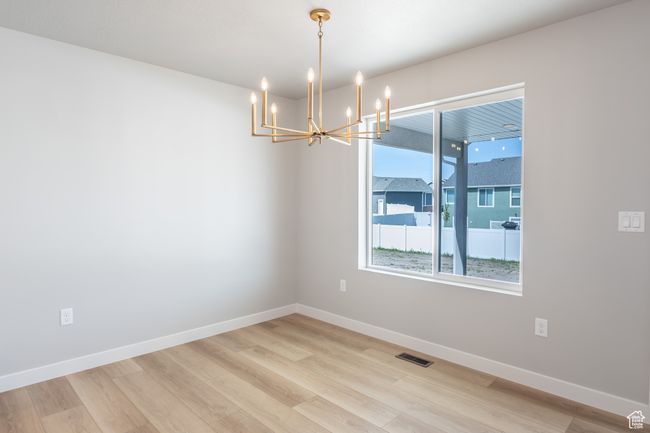 Empty room featuring a chandelier, light wood-style flooring, and baseboards | Image 11