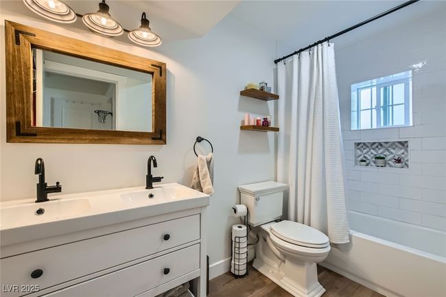 Full bath featuring wood finished floors, double vanity, toilet, and shower / tub combo | Image 24