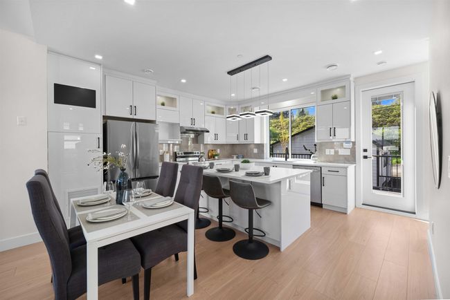 Kitchen with stainless steel appliances, under cabinet range hood, light countertops, white cabinetry, and backsplash | Image 6