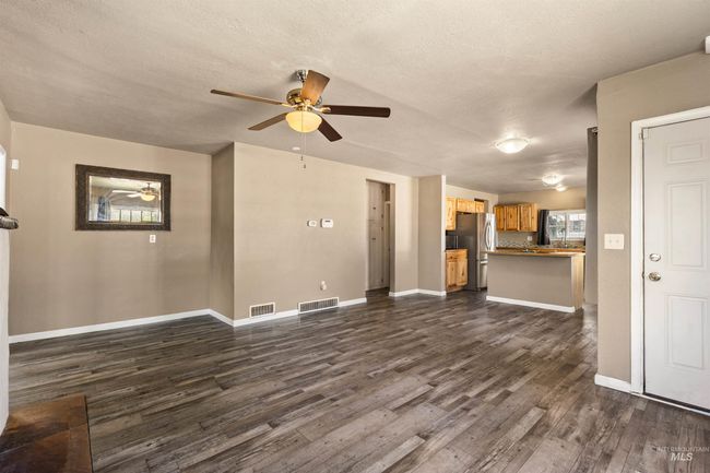 Unfurnished living room featuring a textured ceiling, dark wood-type flooring, and a ceiling fan | Image 9