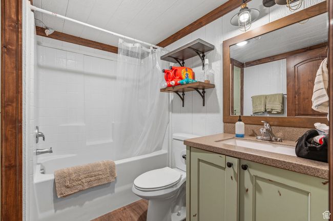 Full bathroom with vanity, wood-type flooring, shower / bathtub combination with curtain, and toilet | Image 55