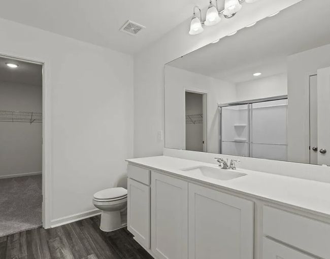 Full bath featuring a spacious closet, vanity, wood finished floors, and a shower with door | Image 9