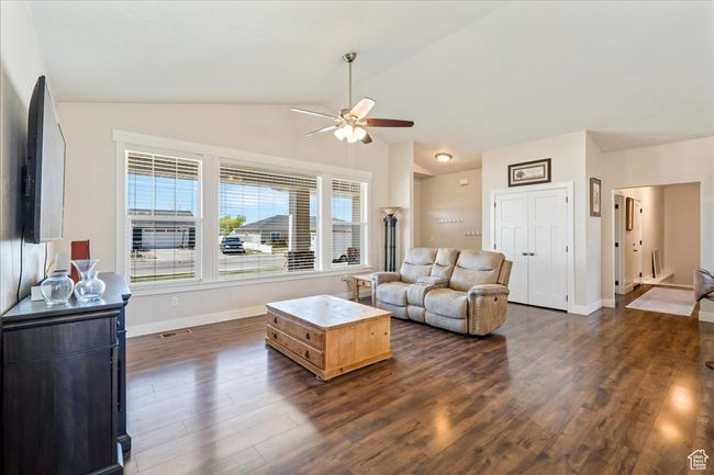 Living room with baseboards, visible vents, lofted ceiling, ceiling fan, and dark wood-type flooring | Image 11