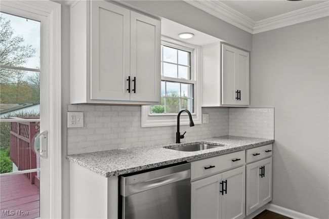 Kitchen with white cabinetry, stainless steel dishwasher, ornamental molding, and a sink | Image 18