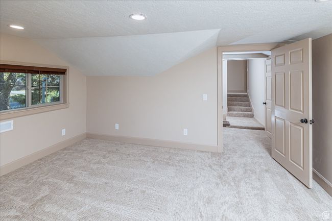 Additional living space with a textured ceiling, carpet, lofted ceiling, stairway, and recessed lighting | Image 33