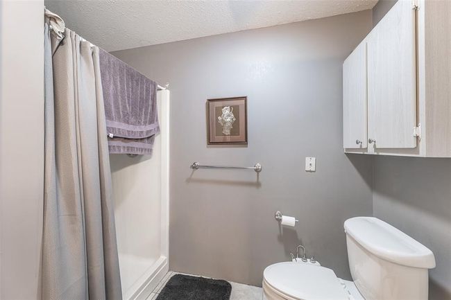 Full bath featuring a shower stall, toilet, a textured ceiling, and baseboards | Image 25