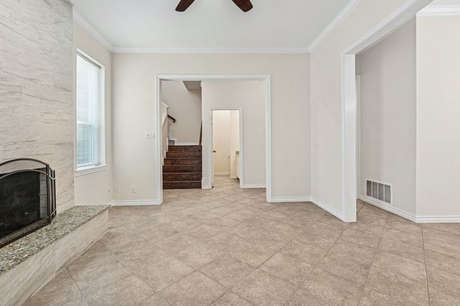 Unfurnished living room featuring a ceiling fan, ornamental molding, stairway, and a premium fireplace | Image 5