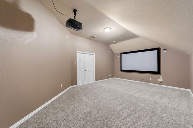 Cinema room featuring carpet floors, vaulted ceiling, baseboards, and a textured ceiling | Image 34