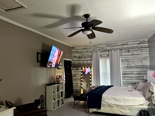 Bedroom featuring wooden walls, finished concrete floors, crown molding, and ceiling fan | Image 16