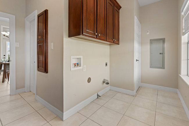 Laundry/utility room showing washer/dryer area, more cabinets & closet for storage, natural light, built in ironing board and the closed door is to the full bath. Open door is out to the kitchen breakfast area. | Image 35
