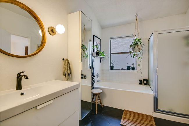 Primary bathroom features a soaking garden tub, separate shower, and tall cabinet mirror. | Image 13