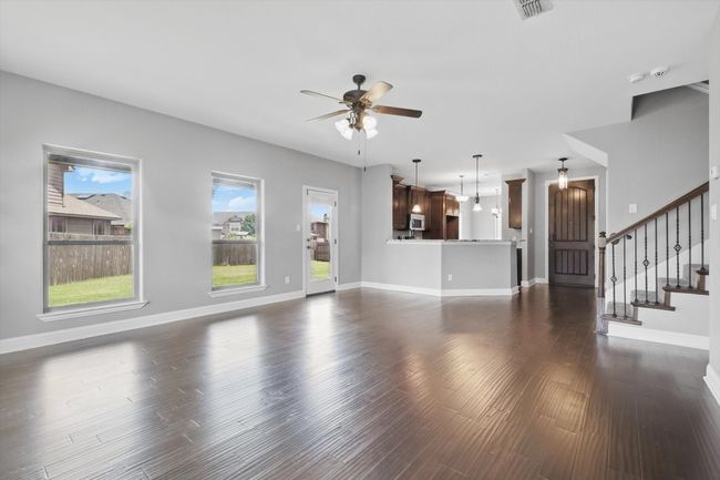Unfurnished living room with ceiling fan, baseboards, stairway, and dark wood-style flooring | Image 15
