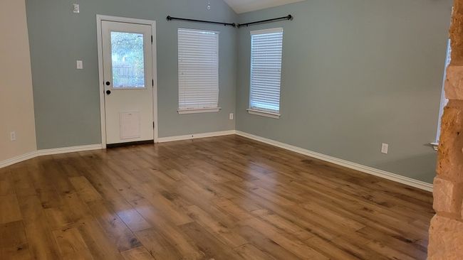 Empty room with wood finished floors, baseboards, lofted ceiling, and healthy amount of natural light | Image 9