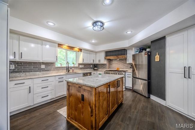 Kitchen featuring appliances with stainless steel finishes, white cabinetry, dark wood-style floors, backsplash, and recessed lighting | Image 18