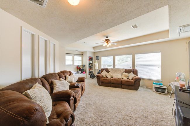 This spacious living room features plush brown sofas, large windows offering plenty of natural light, and a ceiling fan. The neutral walls and carpet create a cozy atmosphere, perfect for relaxation or entertaining. | Image 26