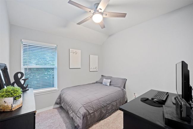 Carpeted bedroom with baseboards, vaulted ceiling, an office area, and a ceiling fan | Image 10