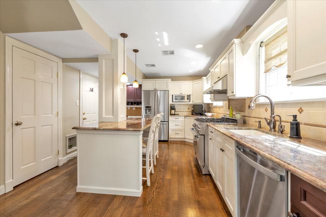 Kitchen with dark wood-style floors, light stone countertops, stainless steel appliances, and visible vents | Image 6