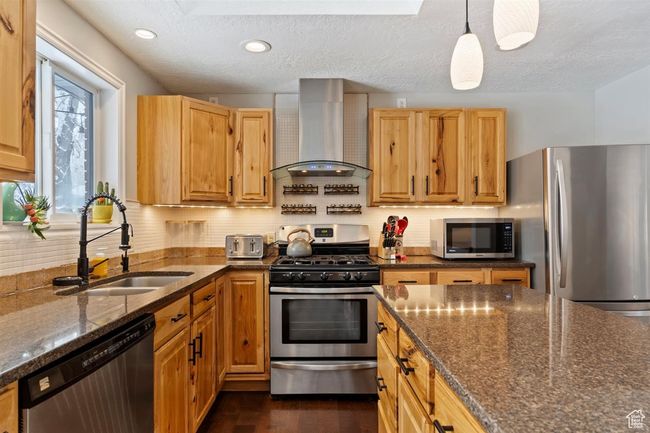 Kitchen with wall chimney range hood, stainless steel appliances, a sink, dark stone counters, and tasteful backsplash | Image 16