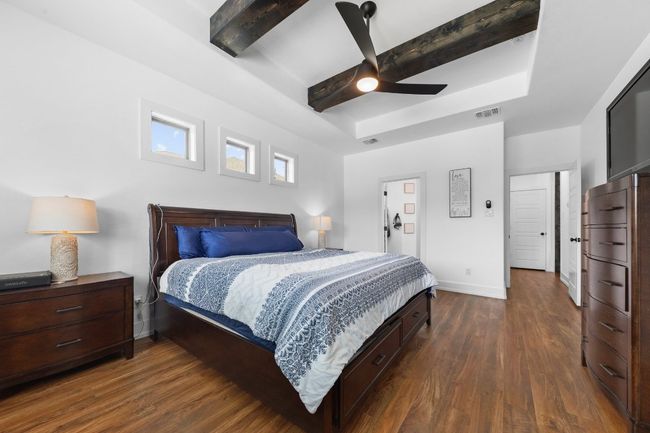 Bedroom featuring a tray ceiling, baseboards, dark wood-style floors, and visible vents | Image 19