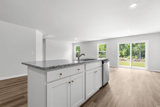 Kitchen with sink, stainless steel dishwasher, white cabinets, hardwood / wood-style flooring, and a kitchen island with sink | Image 19