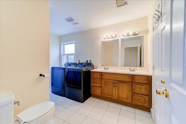 Bathroom featuring toilet, visible vents, washer and clothes dryer, and double vanity | Image 19