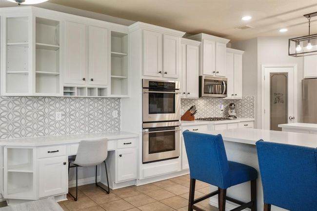 A built-in desk with a quartz counter top sits just between the kitchen and breakfast room complete with upper cabinets and display shelves. | Image 16