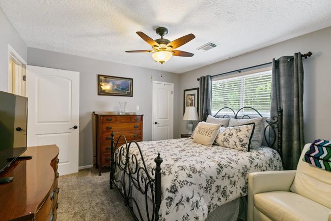 Comfortable secondary bedroom located upstairs. This inviting space features good natural light and a ceiling fan, providing a cozy retreat for family or guests. | Image 23