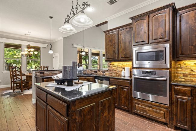 Kitchen featuring appliances with stainless steel finishes, a chandelier, healthy amount of natural light, a center island, and crown molding | Image 18