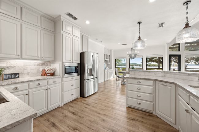 Kitchen with stainless steel appliances, white cabinetry, tasteful backsplash, light wood-style floors, and recessed lighting | Image 18