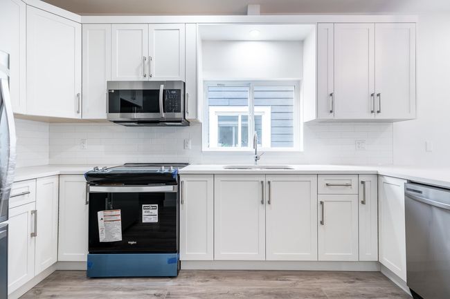 Kitchen featuring appliances with stainless steel finishes, a sink, and white cabinetry | Image 10
