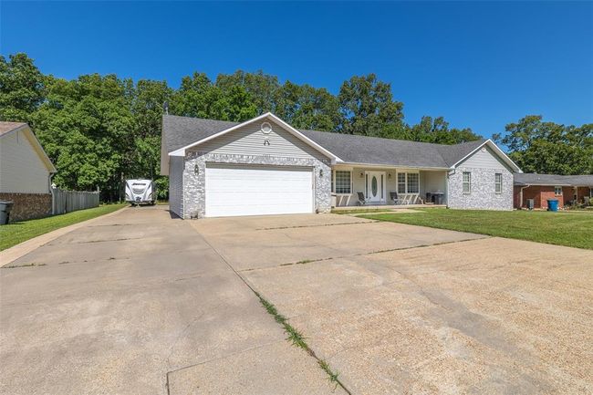 Ranch-style house with a garage, driveway, a porch, brick siding, and roof with shingles | Image 4