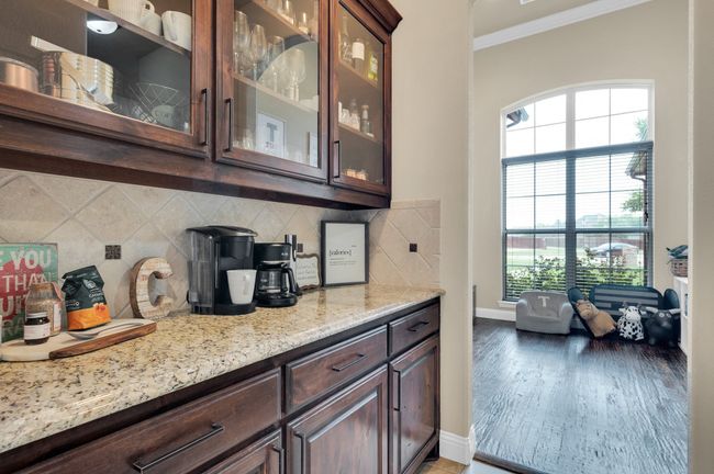 Bar area with ornamental molding, baseboards, healthy amount of natural light, decorative backsplash, and light wood-type flooring | Image 12