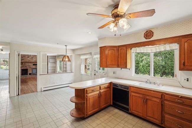 Kitchen featuring baseboard heating, black dishwasher, wallpapered walls, and a sink | Image 8