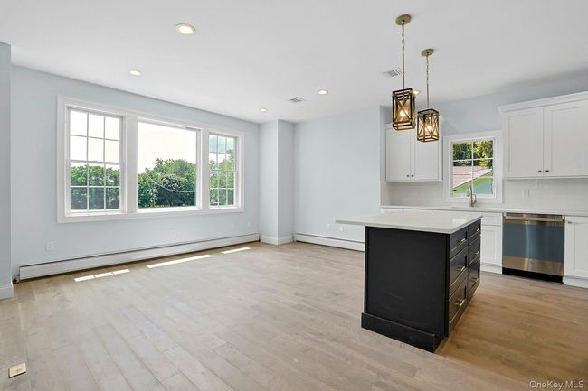 Kitchen with light countertops, dishwasher, a baseboard heating unit, light wood finished floors, and recessed lighting | Image 11